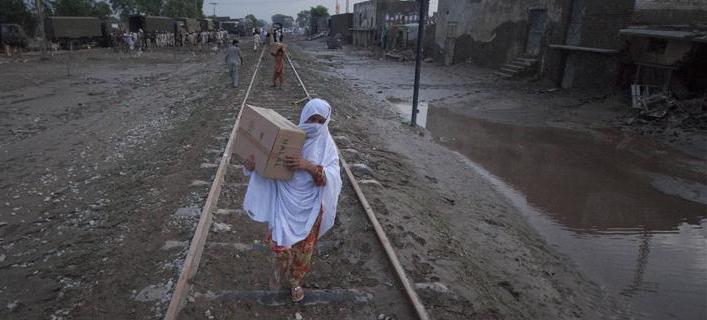 Pakistan flood: A woman carries relief supplies, distributed by the Army